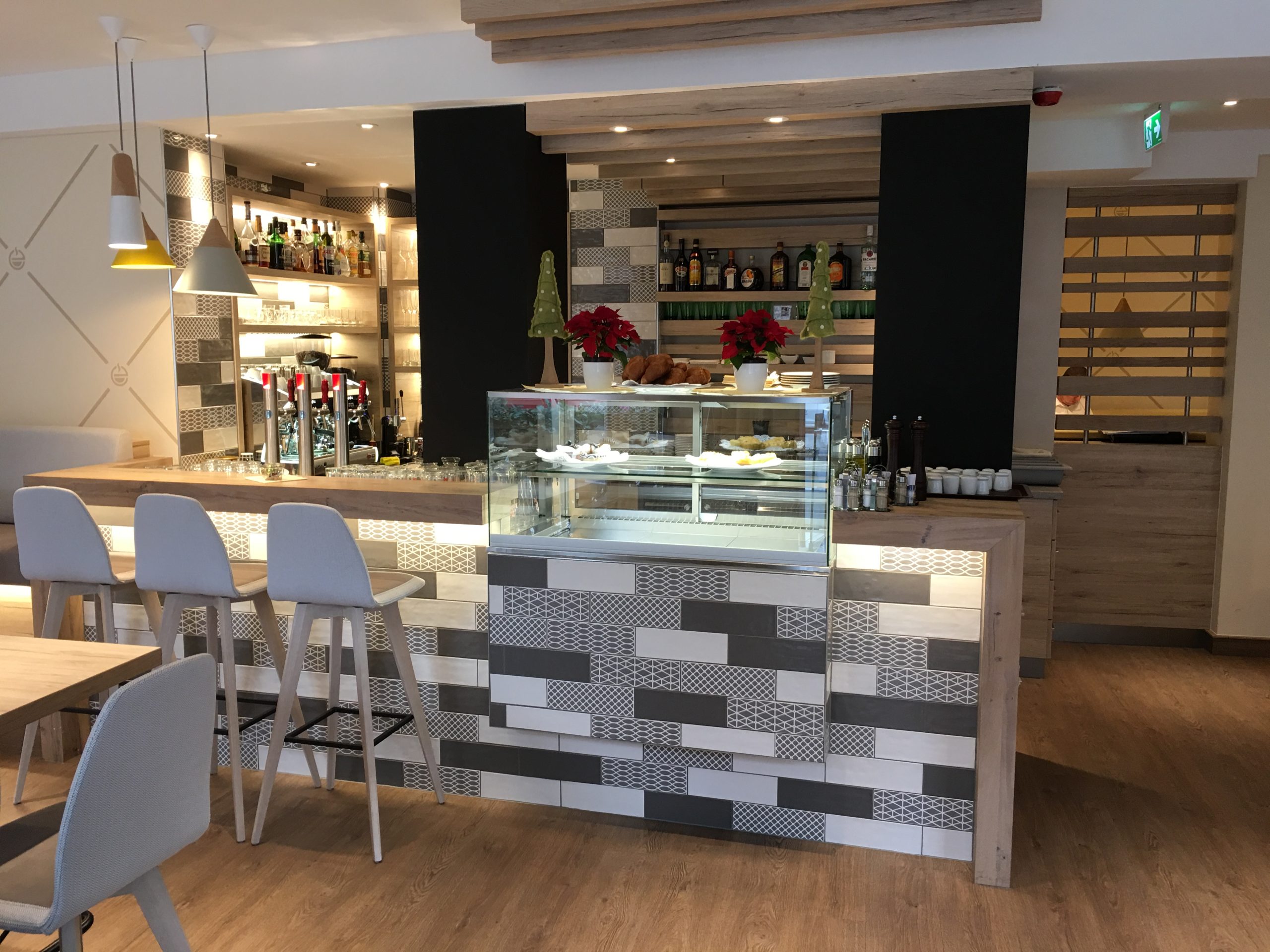 Bar mit gemusterter Front, Hockern und offenem Regal für Spirituosen