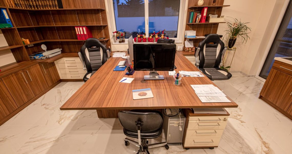 Büro mit großem Arbeitstisch, Bücherwand, Stauraum und Chefsesseln