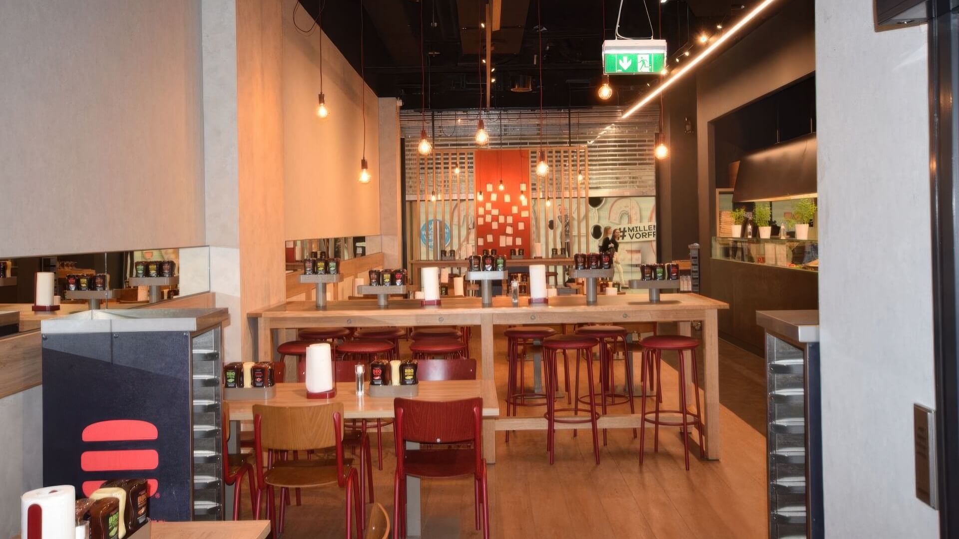 Restaurant mit Hochtischen, roten Barhockern und Spenderstation