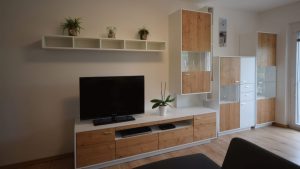 Gesamtansicht Wohnzimmerwand mit TV, Regalen und Vitrinen