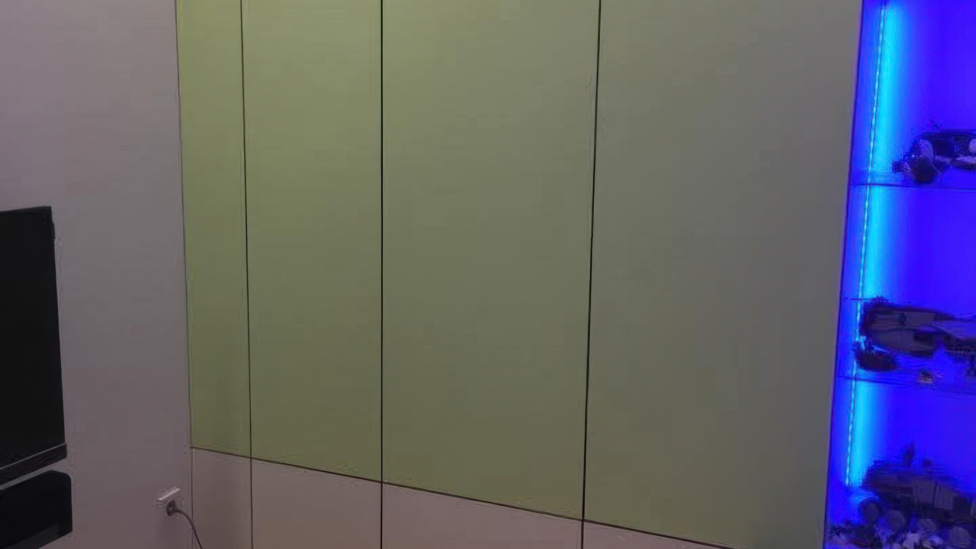 Detailansicht vom grün-weißen Schrank mit LED-beleuchtetem Regal