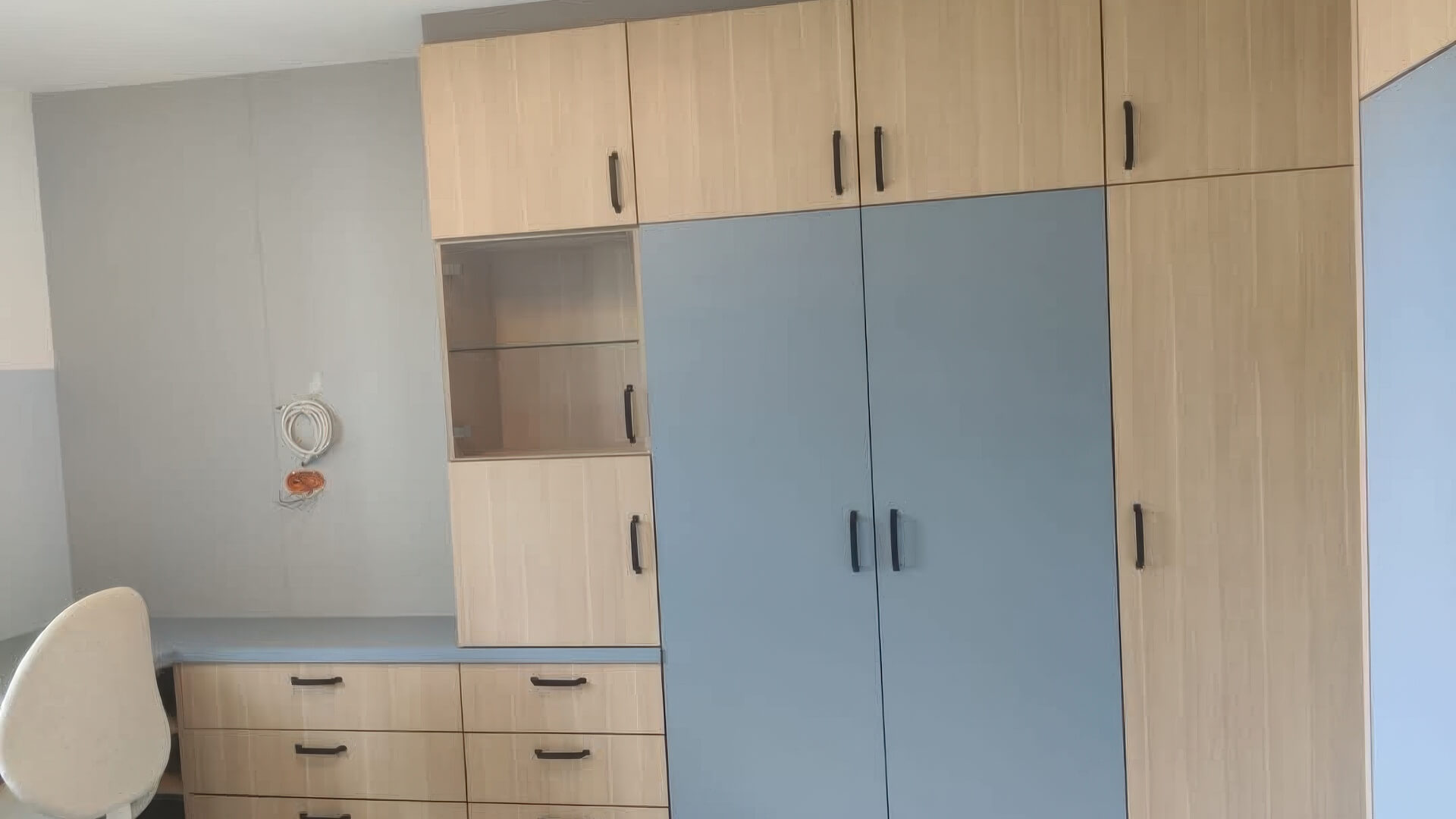 Möbelwand mit blauen und eichefarbenen Fronten, integriertem Arbeitsplatz