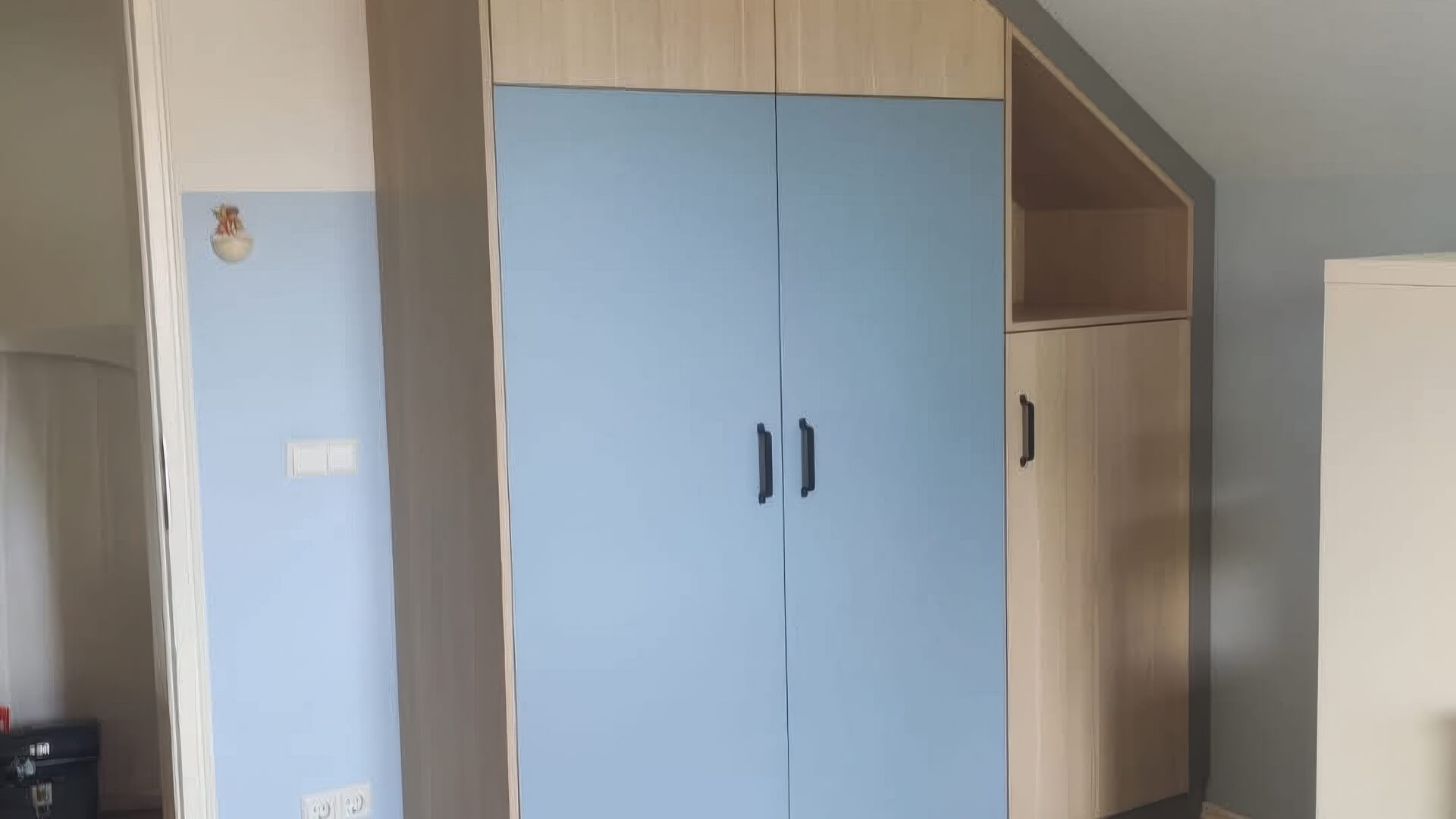 Blauer Einbauschrank mit Schrägenanschluss und offener Ablage