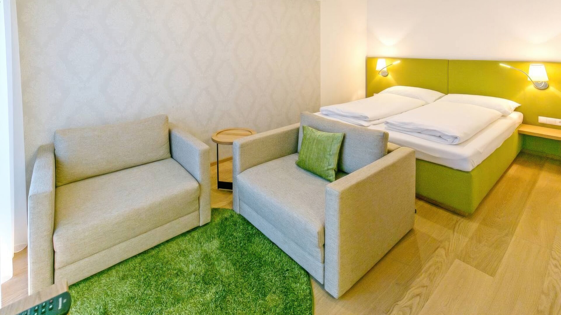 Hotelzimmer mit grüner Polstertapezierung und Sofa