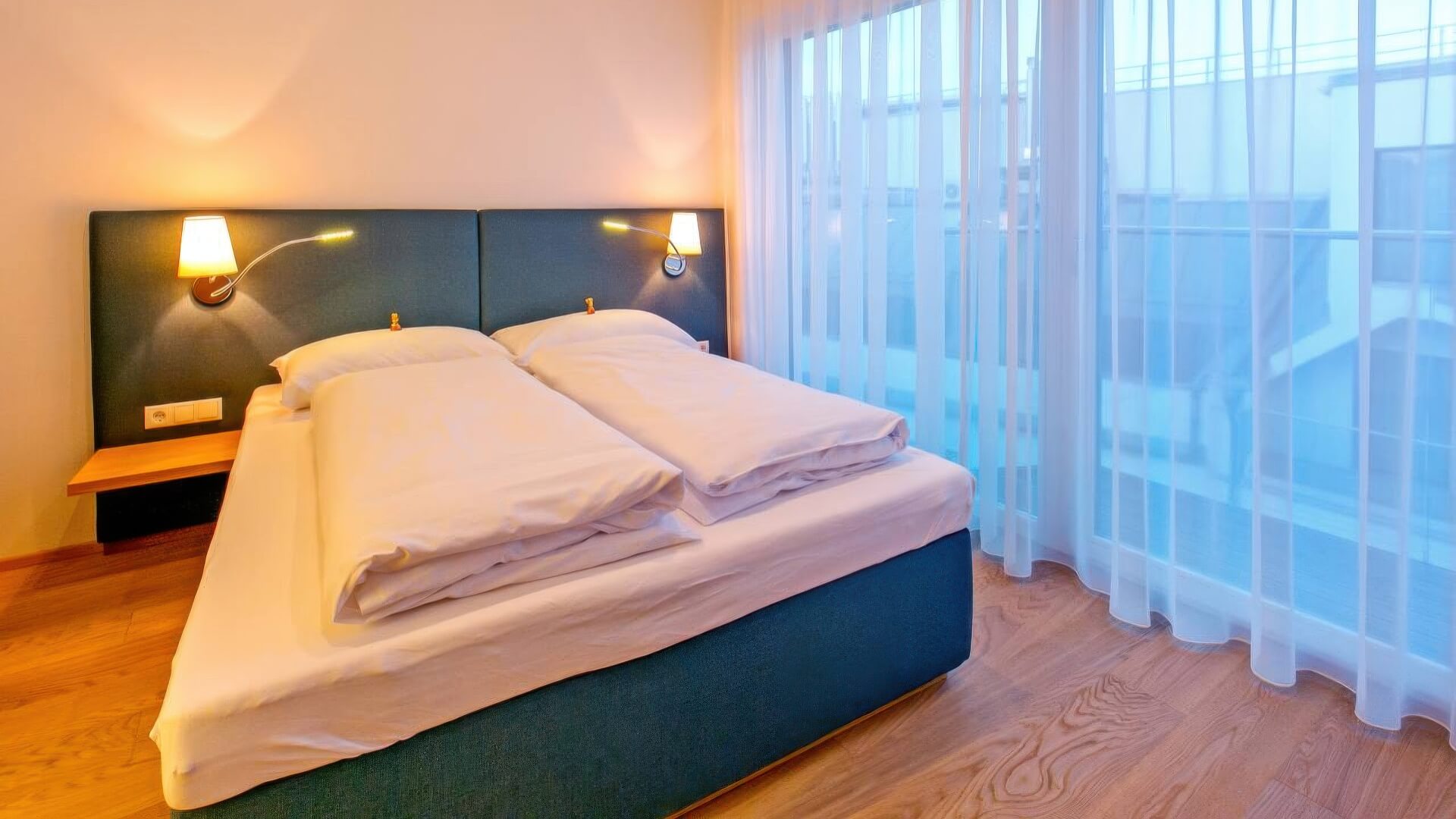 Schlafzimmer mit tapeziertem Bettkopfteil und Vorhangwand