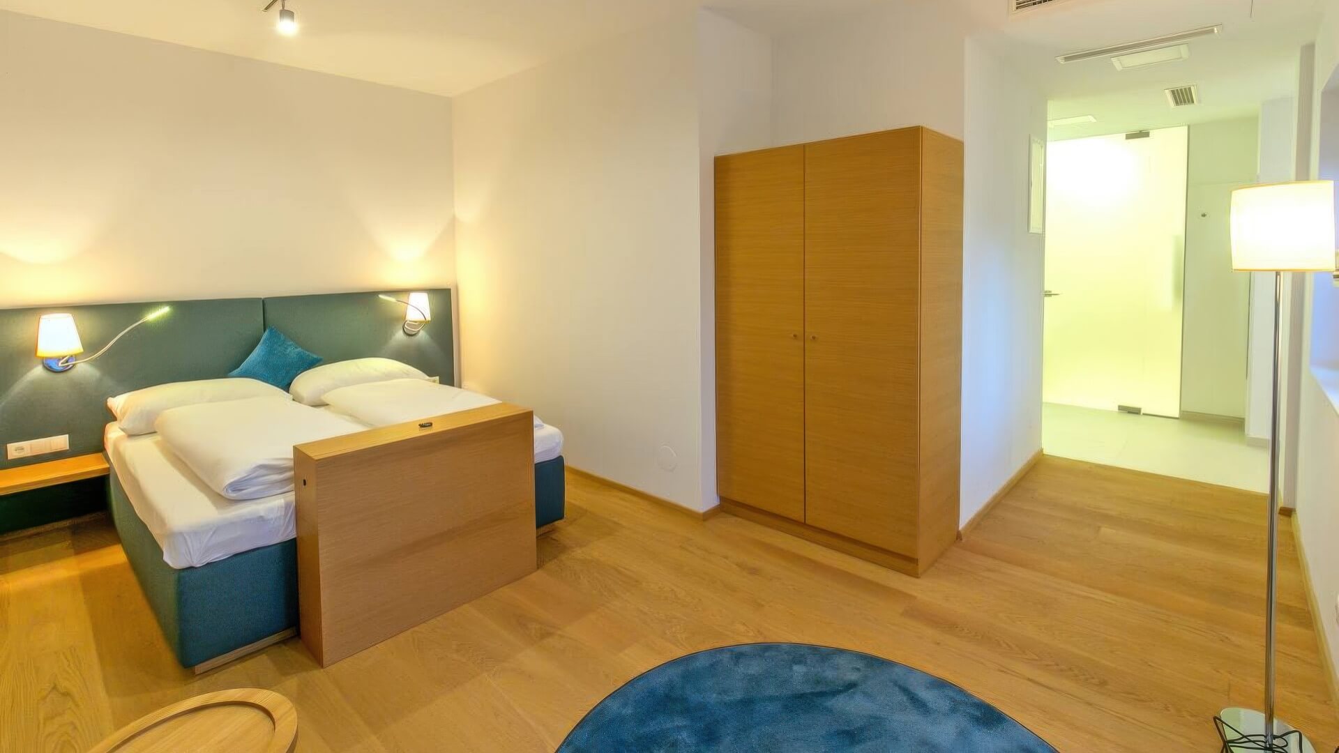 Hotelzimmer mit Bett, Schrank und tapeziertem Kopfteil
