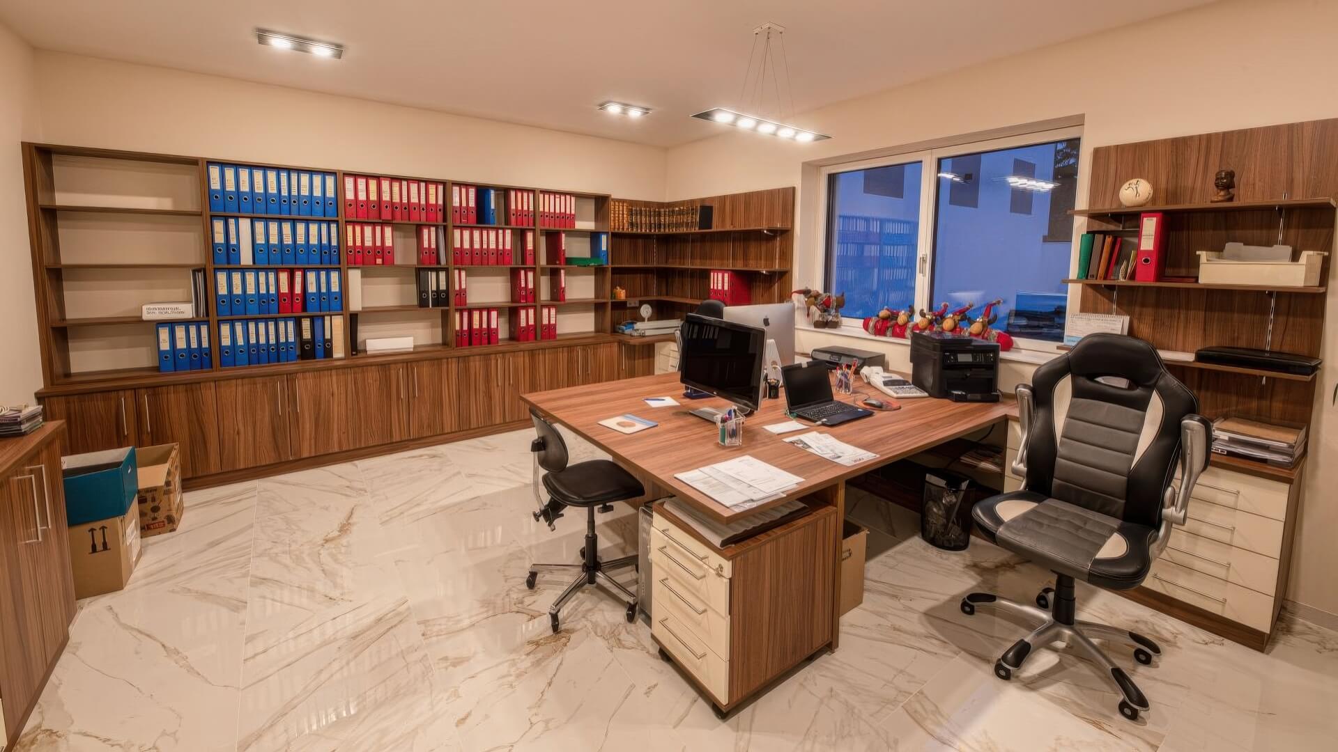 Büro mit zwei Schreibtischen und großem Regal für Ordner