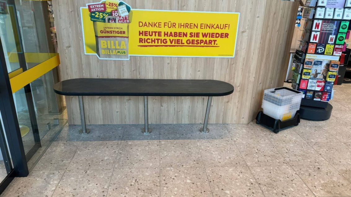 Sitzbank vor Holzpaneelwand mit Werbebotschaft im Eingangsbereich