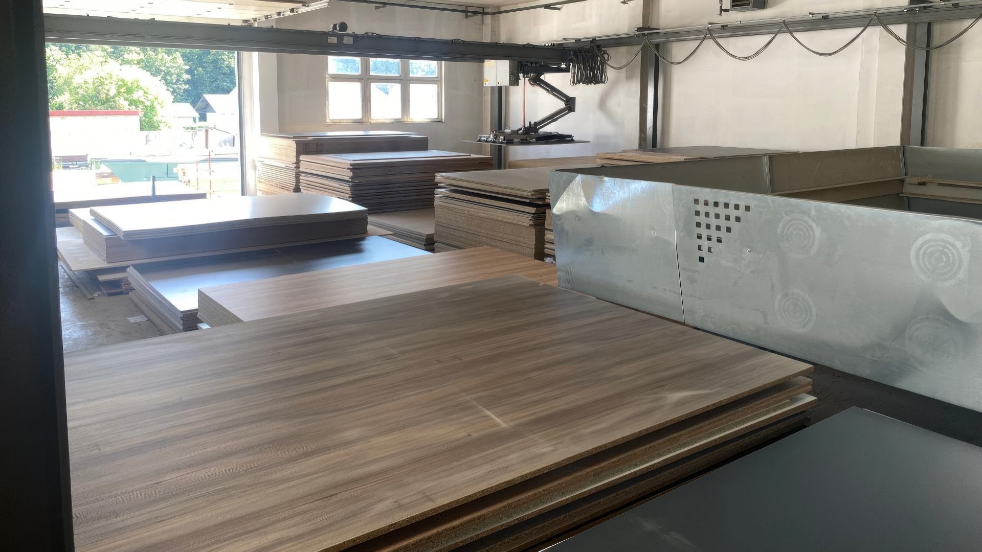 Stapel von Holzwerkstoffplatten in verschiedenen Dekoren im Lagerbereich mit Tageslicht