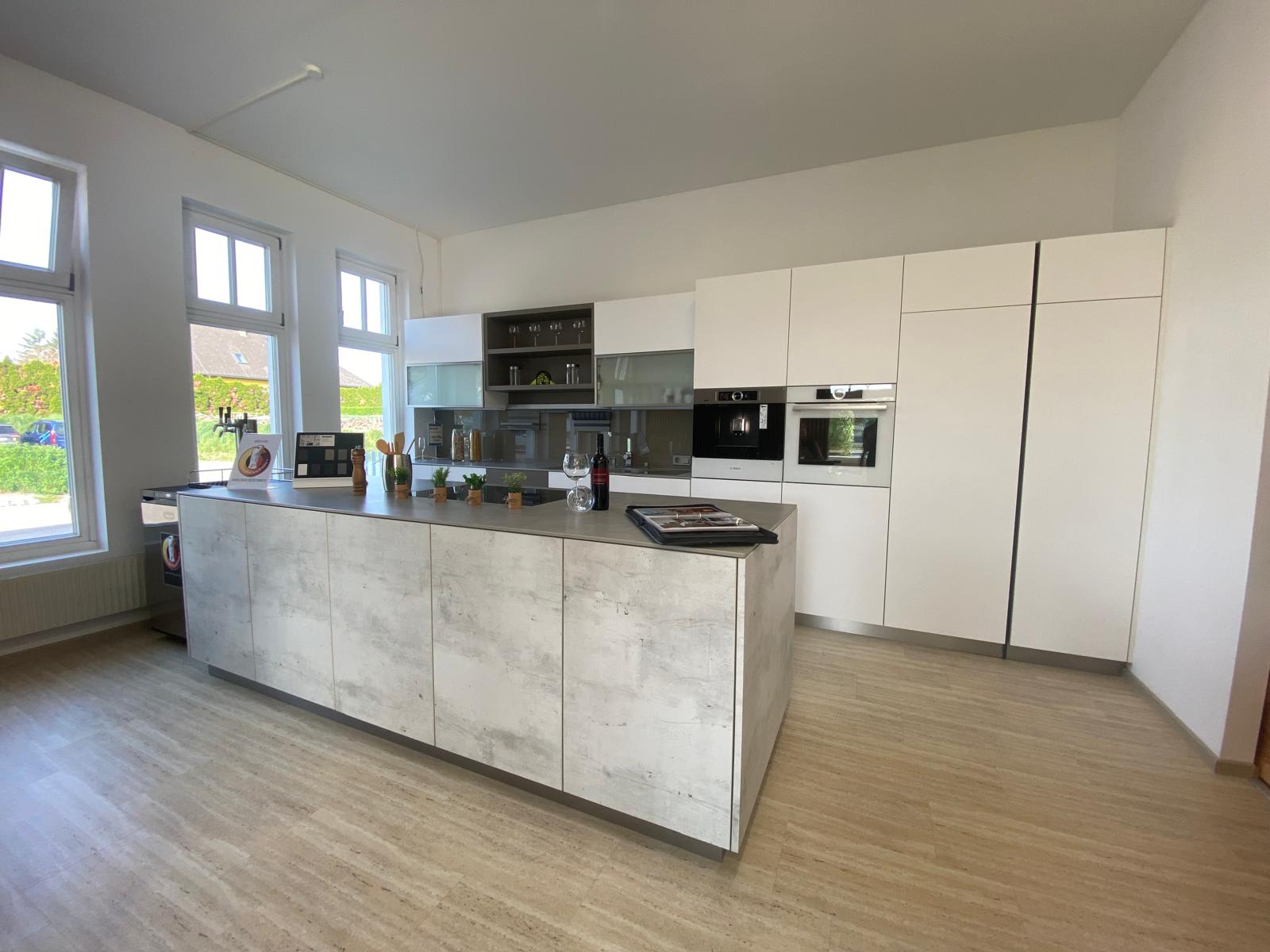 Küchenlösung in Betonoptik mit Kochinsel – Maßanfertigung der ROKU Tischlerei Moderne Einbauküche mit Kochinsel in Betonoptik und hochgebauten Geräten
