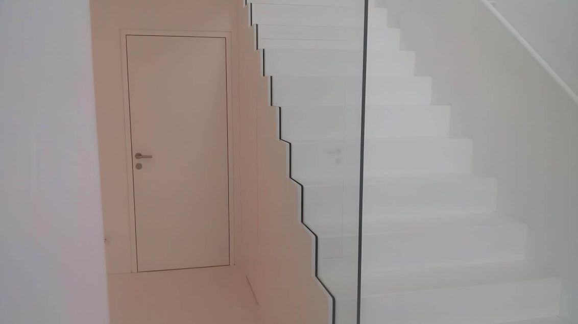Schrankverkleidung unter weißer Stiege mit bündiger Tür